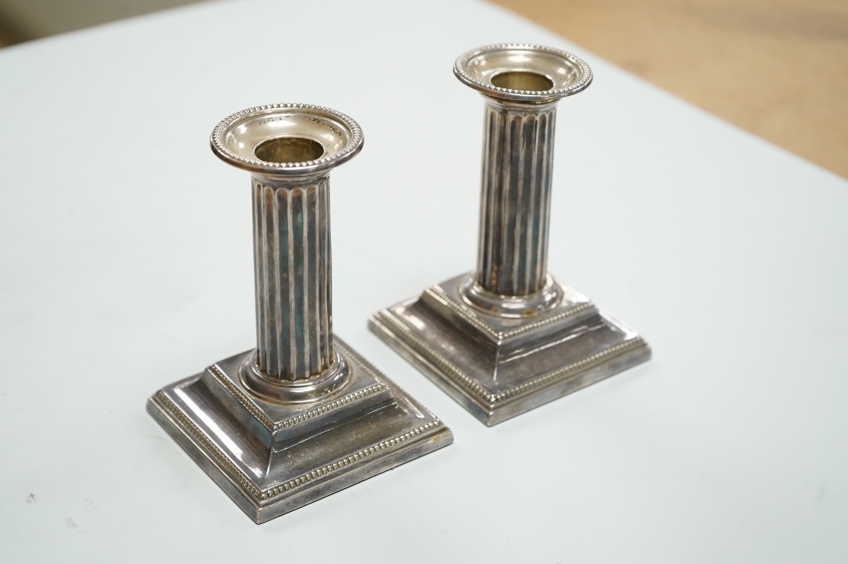 A pair of Edwardian silver mounted fluted column candlesticks, by Hawksworth, Eyre & Co, Sheffield, 1905/6, height 12cm, weighted.